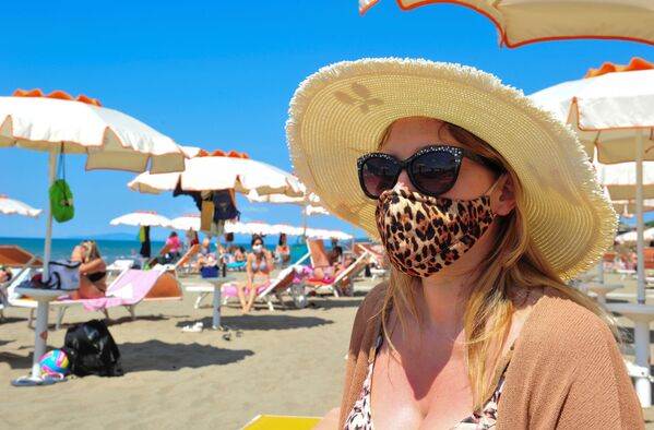 Женщина в защитной маске и солнцезащитных очках на пляже в Кастильоне-делла-Пеская, Италия - Sputnik Молдова
