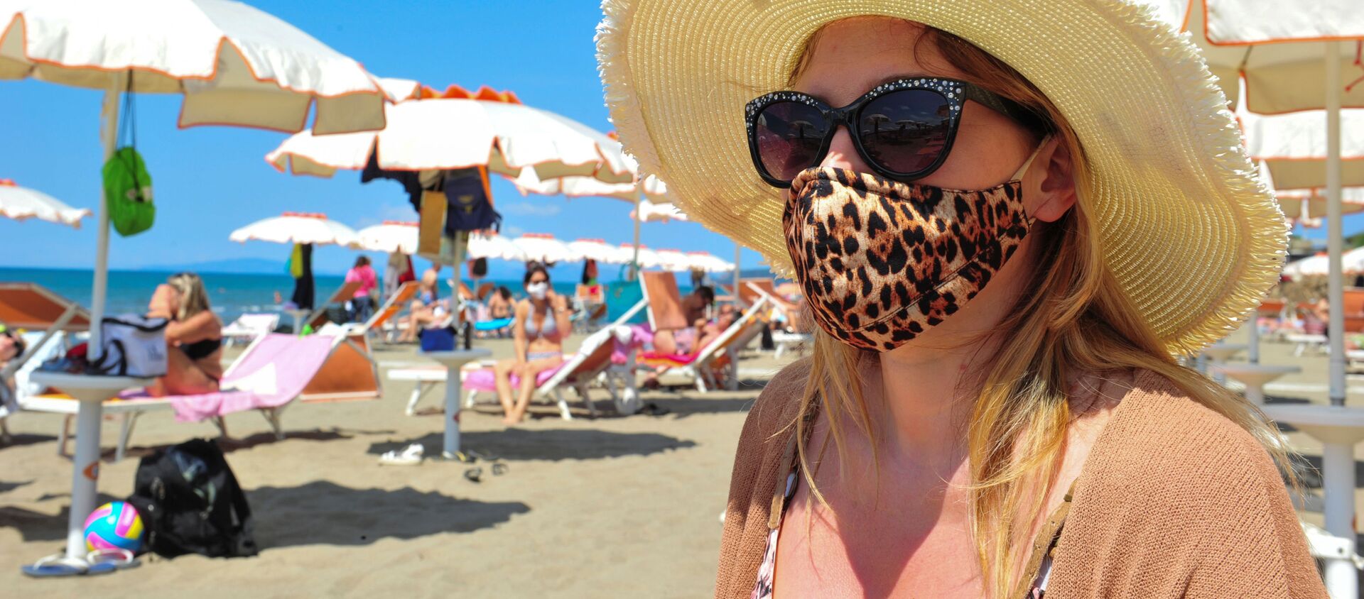Женщина в защитной маске и солнцезащитных очках на пляже в Кастильоне-делла-Пеская, Италия - Sputnik Молдова, 1920, 28.06.2020
