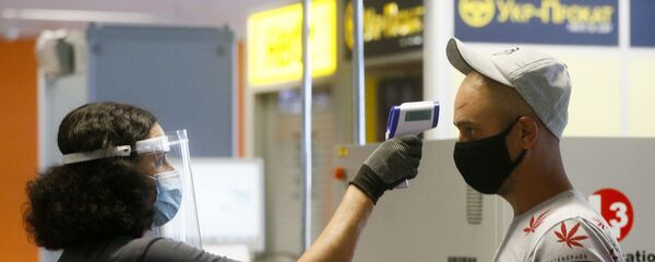 Пассажир в защитной маске проходит температурный контроль в международном аэропорту Борисполь в Киеве - Sputnik Moldova