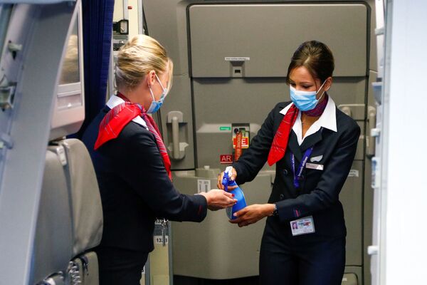 Стюардессы в медицинских масках обрабатывают руки антисептическим гелем в салоне самолета в международном аэропорту Брюсселя - Sputnik Молдова