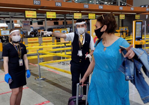 Сотрудники авиакомпании Pegasus Airlines в защитных масках и экранах указывают пассажиру нужное направление в международном аэропорту имени Сабихи Гекчен в Стамбуле - Sputnik Молдова