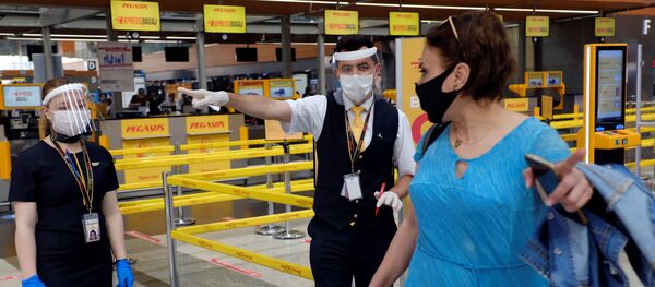 Сотрудники авиакомпании Pegasus Airlines в защитных масках и экранах указывают пассажиру нужное направление в международном аэропорту имени Сабихи Гекчен в Стамбуле - Sputnik Молдова