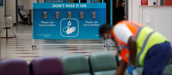 Сотрудник по уборке в маске и перчатках дезинфицирует сиденья в аэропорту Гатвик, Великобритания - Sputnik Moldova