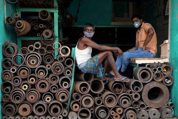 Рабочие в защитных масках в магазине, торгующем железными трубами на оптовом рынке в Калькутте, Индия - Sputnik Молдова