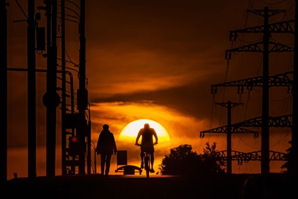 Мужчина едет на велосипеде по одной из улиц в Москве на фоне заката - Sputnik Молдова