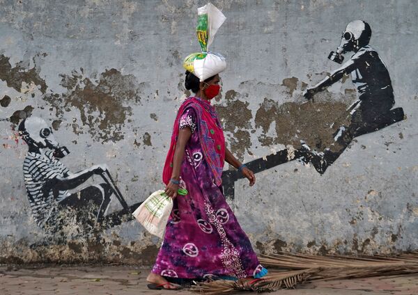 Женщина в защитной маске проходит мимо граффити в Мумбаи, Индия - Sputnik Молдова