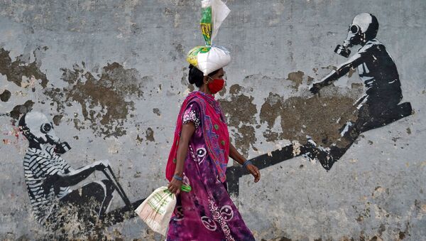 Женщина в защитной маске проходит мимо граффити в Мумбаи, Индия - Sputnik Молдова