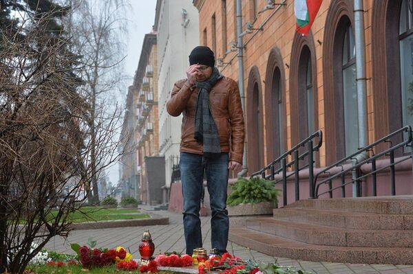 Минчанин у посольства Франции в Минске. Несмотря на ненастную погоду белорусы несут цветы к зданию дипмиссии. - Sputnik Молдова