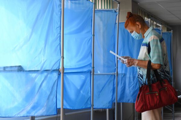 Женщина принимает участие в голосовании по внесению поправок в Конституцию РФ на избирательном участке №1503 в Новосибирске - Sputnik Moldova
