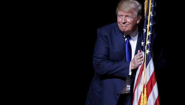 U.S. Republican presidential candidate Donald Trump hugs a U.S. flag as he takes the stage for a campaign town hall meeting in Derry, New Hampshire August 19, 2015 - Sputnik Moldova