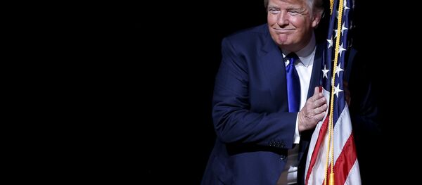 U.S. Republican presidential candidate Donald Trump hugs a U.S. flag as he takes the stage for a campaign town hall meeting in Derry, New Hampshire August 19, 2015 - Sputnik Moldova