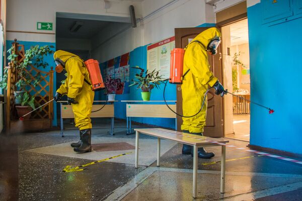 Сотрудники МЧС в защитных костюмах во время санитарной обработки избирательного участка в Тверской области - Sputnik Молдова
