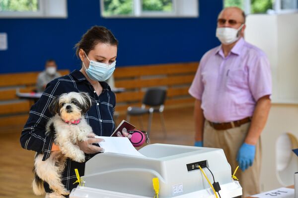 Девушка с собачкой голосует по вопросу одобрения изменений в Конституцию России на избирательном участке в Москве - Sputnik Moldova-România