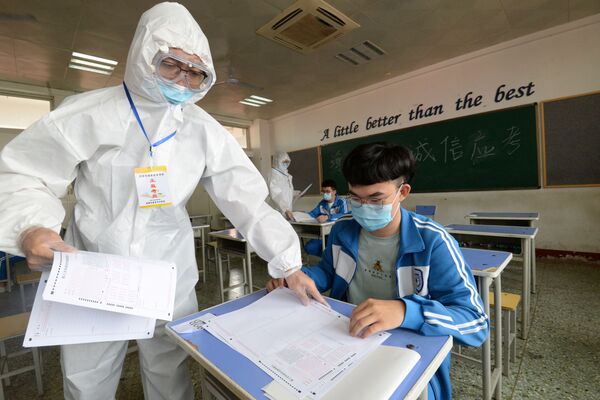 Экзаменатор раздает тестовые задания студентам на предварительном экзамене в Хандане, Китай - Sputnik Молдова
