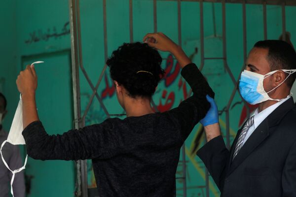 Охранник в защитной маске проверяет старшеклассника перед экзаменами в Каире, Египет - Sputnik Молдова