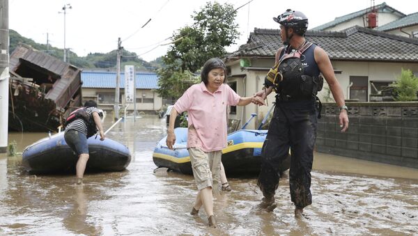 Спасатель помогает женщине во время эвакуации в японской префектуре Кумамото - Sputnik Moldova-România