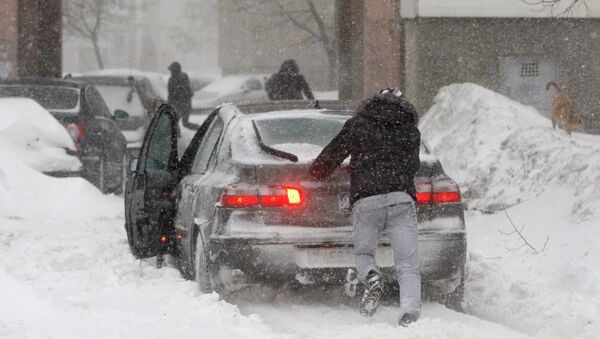 Местный житель толкает автомобиль, застрявший в снегу - Sputnik Молдова