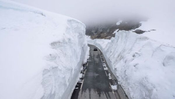 Автомобиль проезжает мимо стены снега по горной дороге в Норвегии - Sputnik Moldova-România