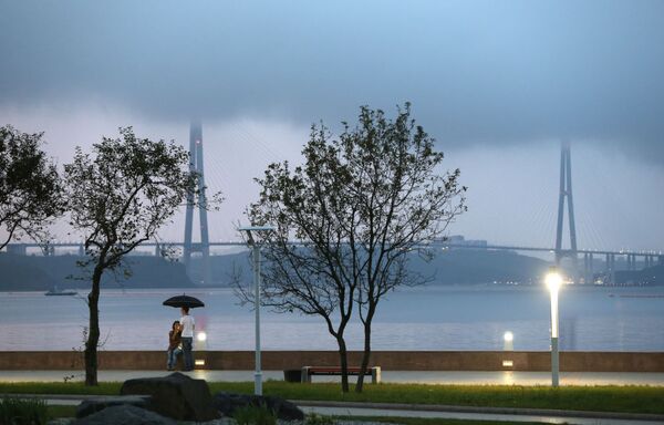 Молодые люди вечером на набережной острова Русский во Владивостоке на фоне вантового моста через пролив Босфор Восточный - Sputnik Молдова
