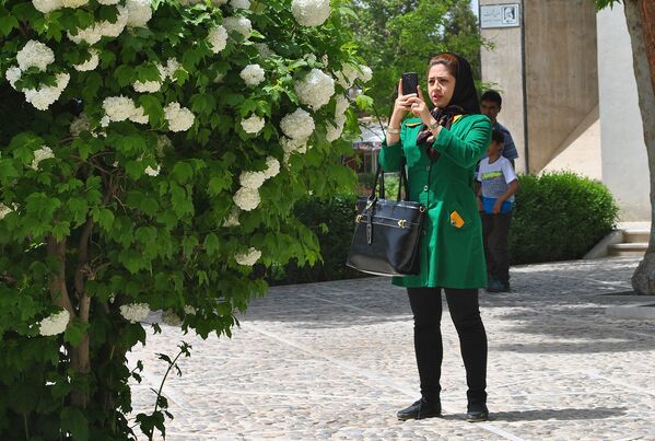 Девушка фотографирует цветы у мавзолея Абулькасима Фирдоуси. - Sputnik Молдова