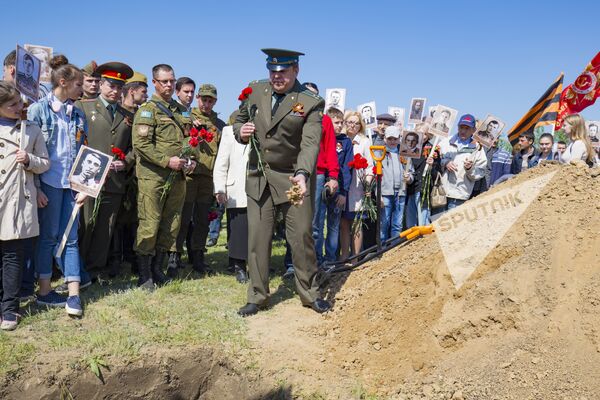 Cei prezenți aruncă o mână de țărână peste viitorul mormânt al ostașilor-eliberatori. - Sputnik Moldova