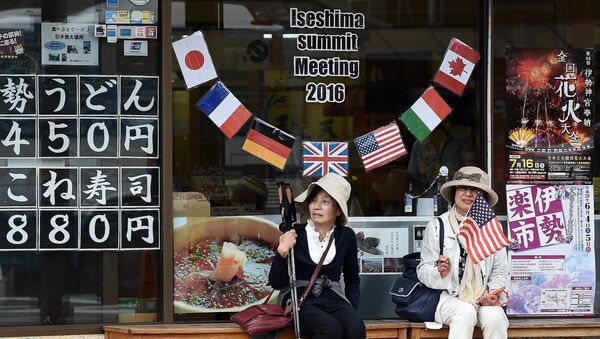 Elderly Japanese women sit under a welcome message outside a shop during the world leaders' visit to the Ise-Jingu Shrine in the city of Ise, Mie prefecture on May 26, 2016 on the first day of the G7 leaders summit - Sputnik Молдова