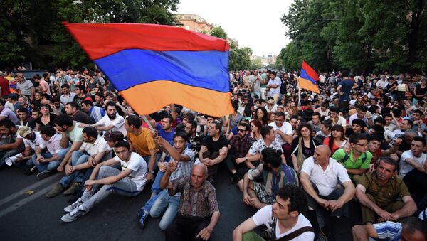 Demonstrators wave their national flags as they sit during a protest against the increase of electricity prices in Yerevan, the capital of Armenia, on June 22, 2015. - Sputnik Moldova