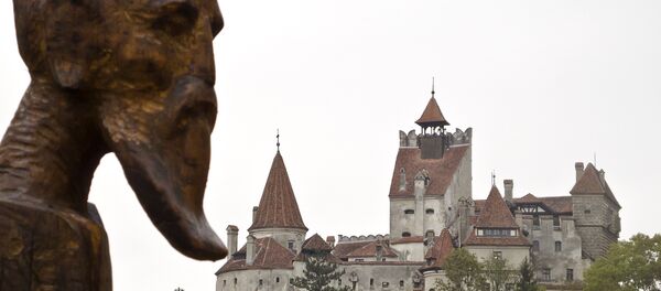 A sculpture commemorating Petru Darascu, a Romanian priest who survived several Communist prisons, by Ovidiu Nicolae Popa is backdropped by the Gothic Bran Castle, better known as Dracula Castle, in Bran, in Romania's central Transylvania region, Saturday, Oct. 8, 2011 - Sputnik Moldova-România
