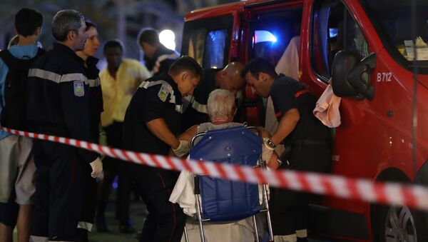 Rescue workers help an injured woman to get in a ambulance on July 15, 2016, after a truck drove into a crowd watching a fireworks display in the French Riviera town of Nice. - Sputnik Moldova