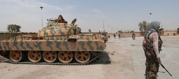 A Kurdish fighter from the People's Protection Units (YPG) carries his weapon as he stands past a tank in the Ghwairan neighborhood of Hasaka, Syria, August 22, 2016. - Sputnik Moldova-România