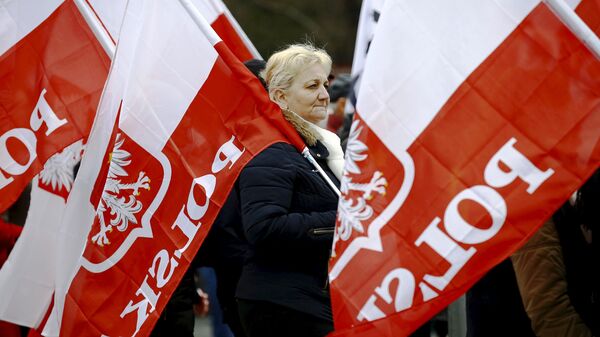 A woman holds the Polish national flag as she takes part in a march demanding their government to respect the country's constitution in Warsaw, Poland, March 12, 2016.  - Sputnik Moldova-România