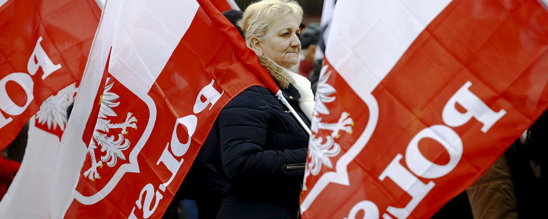A woman holds the Polish national flag as she takes part in a march demanding their government to respect the country's constitution in Warsaw, Poland, March 12, 2016.  - Sputnik Moldova-România, 1920, 16.02.2022