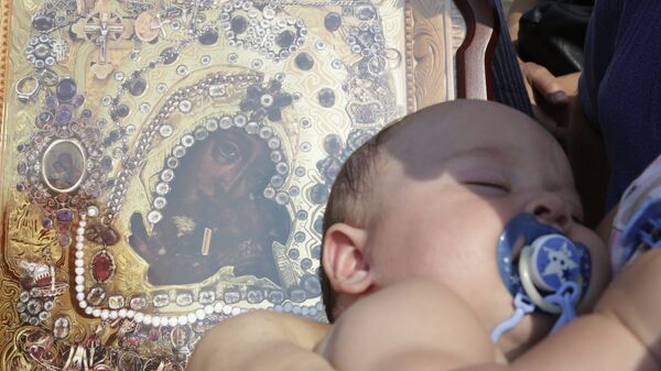 Prunc într-o Biserică ortodoxă lângă icoana Maicii Domnului cu prunul Iisus în brațe, imagine simbolică - Sputnik Moldova
