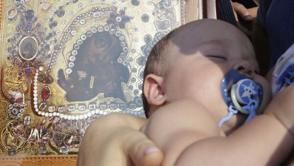 Prunc într-o Biserică ortodoxă lângă icoana Maicii Domnului cu prunul Iisus în brațe - Sputnik Moldova-România