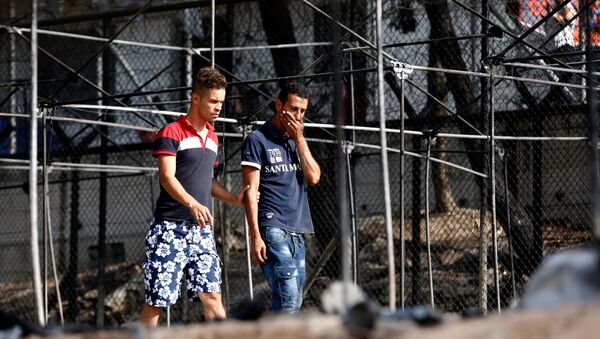 A migrant (R) reacts as he walks next to the remains of burned tents at the Moria migrant camp, after a fire that ripped through tents and destroyed containers during violence among residents, on the island of Lesbos, Greece, September 20, 2016. - Sputnik Moldova
