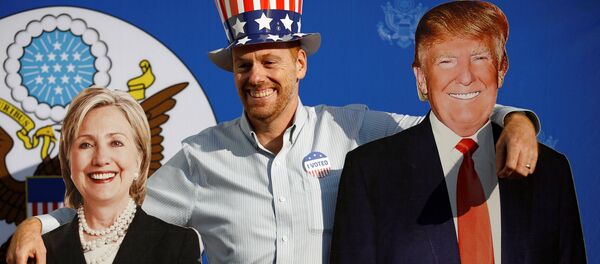 Мужчина позирует с картонными вырезами кандидатов в президенты Хиллари Клинтон и Дональд Трамп - Sputnik Молдова