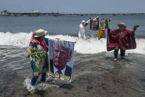Șamani, într-un ritual de preziceri pentru alegerile din SUA, cu afișele candidaților la președinție, Donald Trump și Hilary Clinton la plaja Agua Dulce din Lima, pe 7 noiembrie 2016. - Sputnik Moldova