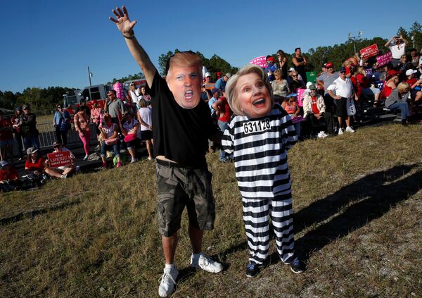 Крейг Вендел и его супруга Джилл в масках Дональда Трампа и Хиллари Клинтон. Примечательно, что вместе с маской Клинтон женщина надела тюремную робу. - Sputnik Молдова