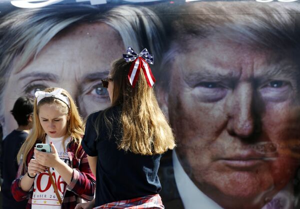 Oamenii pozează lângă un autobuz acoperit cu fotografiile mari ale candidaților Hillary Clinton și Donald Trump, înainte de dezbaterea prezidențială. - Sputnik Moldova