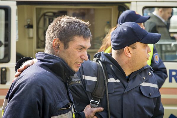 Полицейский помогает пострадавшему пожарному. - Sputnik Молдова
