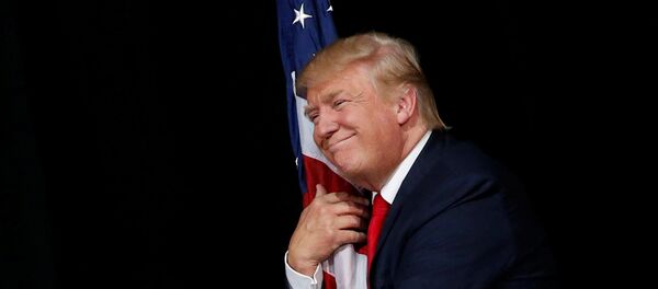 Donald Trump hugs a U.S. flag as he comes onstage to rally with supporters in Tampa, Florida, U.S. October 24, 2016 - Sputnik Moldova-România