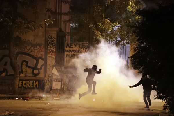 Протестующий уклоняется от заряда со слезоточивым газом во время митинга против визита Барака Обамы в Афины - Sputnik Молдова