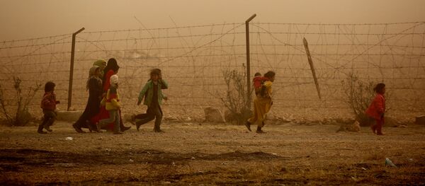 Дети идут вдоль забора во время песчаной бури в лагере беженцев недалеко от деревни Айн Исса, Сирия - Sputnik Moldova-România