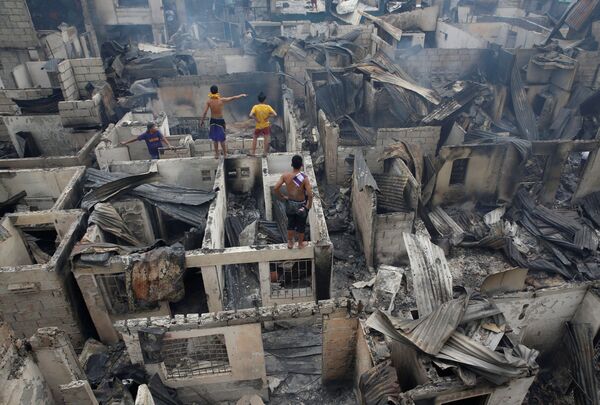 Жители стоят на крыше сгоревшего доме в Мандальюионге, Филиппины - Sputnik Молдова